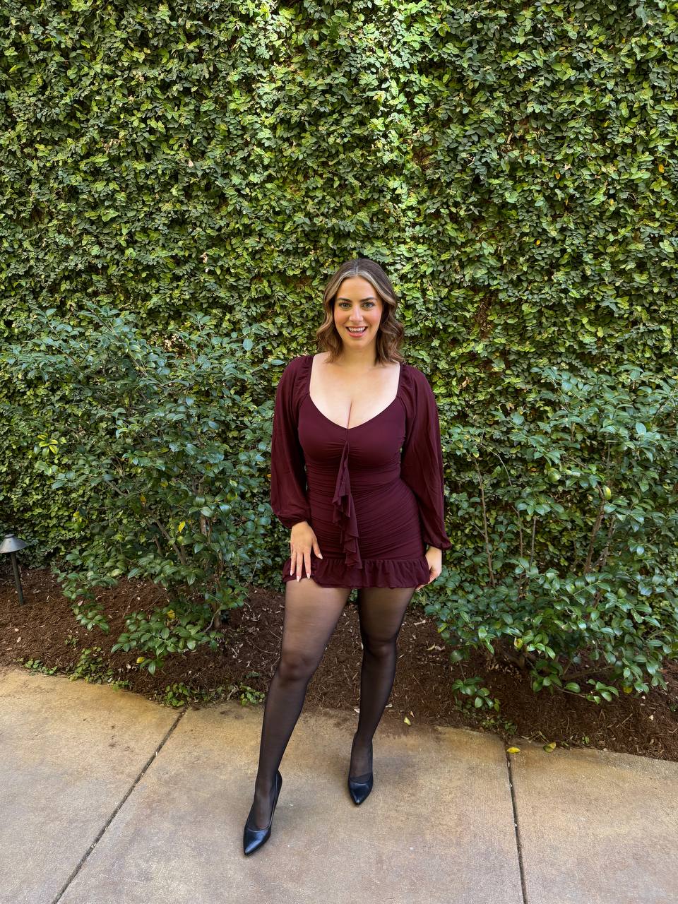 Claire in a burgundy dress and black heels