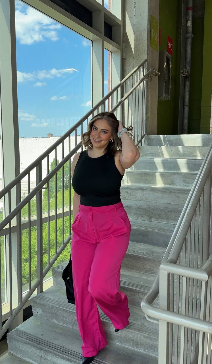 Claire wearing a black top with vivid pink trousers